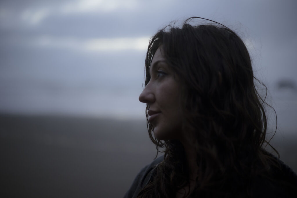 A woman looks off camera dramatically during a cinematic couples session on the Oregon Coast