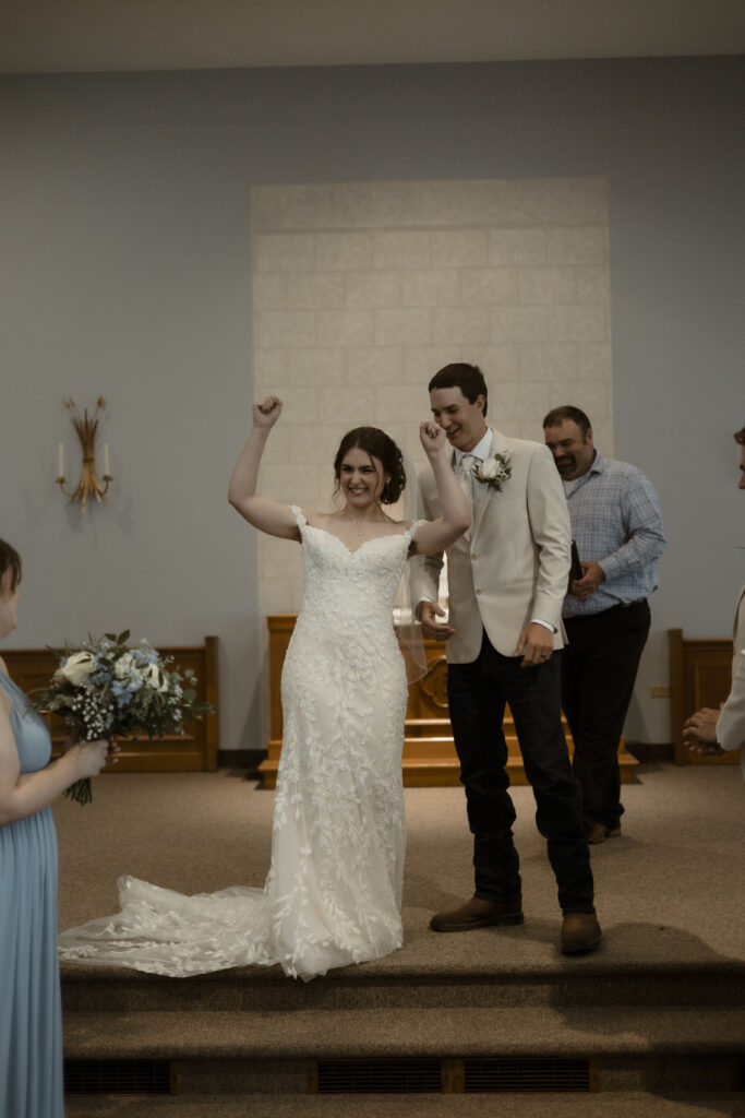 Callie raises her hands in celebration with the crowd as they are announced as husband and wife