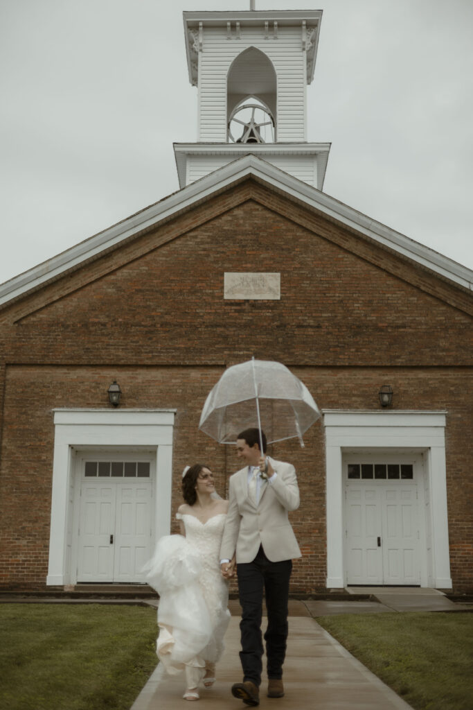 Callie and Matt walk away from the church under an umbrella