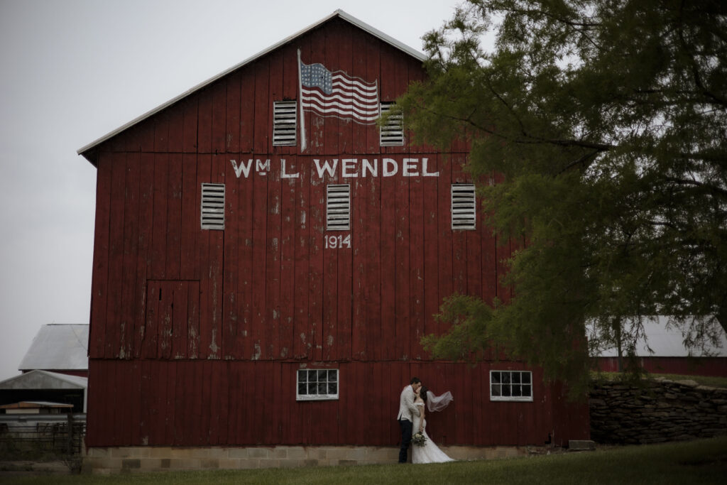 Callie and Matt share a kiss in front of the red barn