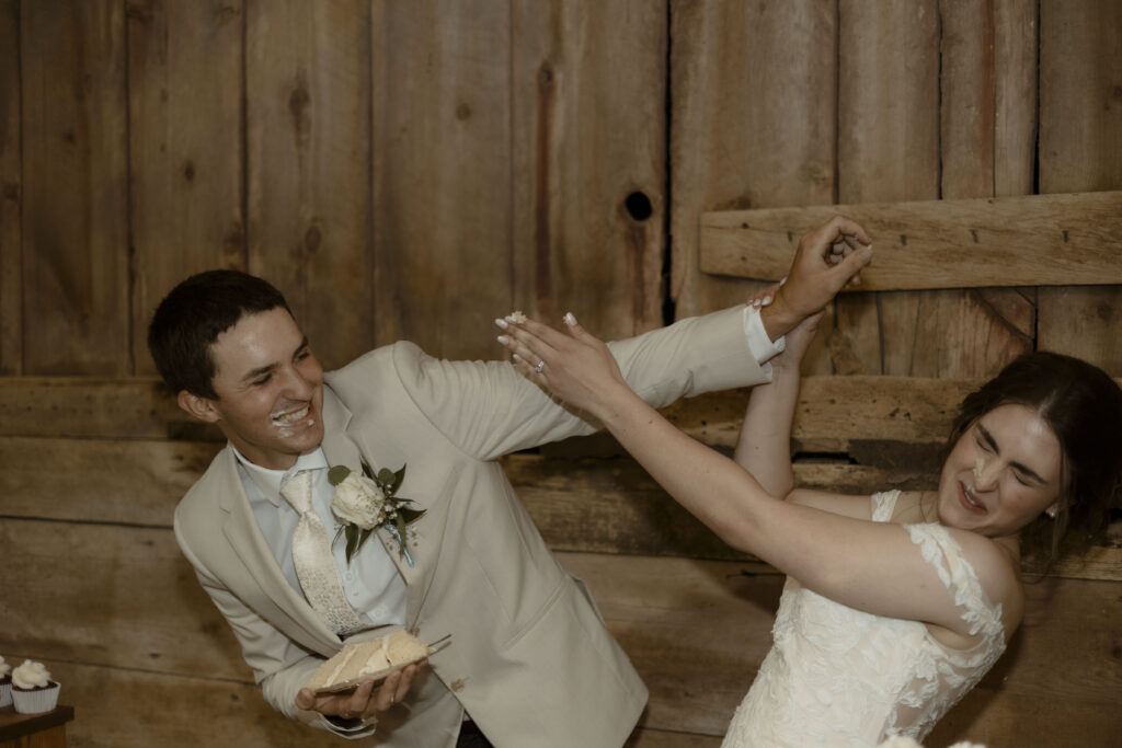 Callie and Matt shove wedding cake at each other while laughing